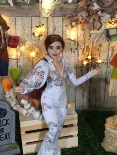 a doll is posed in front of a fake grave with lights and decorations on it