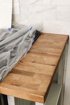 a wooden table with plastic covering it and a white tile backsplash in the background