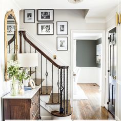 a staircase with pictures on the wall above it and a table in front of it