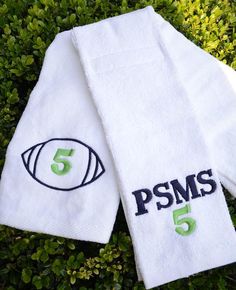 two white towels sitting on top of a green bush next to each other with the letters psms and 5