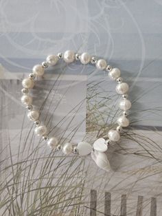 Full pearl bracelet with freshwater pearls all around and mixed with silver spacer beads. In the center is a seashell hanging surrounded by two mother of pearl hearts! 7 Inches White Beaded Pearl Charm Bracelet, White Pearl Beaded Charm Bracelet, White Mother Of Pearl Beaded Bracelet As Gift, White Pearl Stretch Bracelet With Pearl Charm, Pearl Bracelet With Heart Beads For Gifts, White Pearl Beaded Bracelets With Heart Beads, White Pearl Bracelets With Heart Beads, White Pearl Bracelet With Heart Beads, Elegant White Stretch Bracelet With Heart Beads