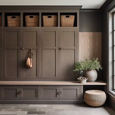 a room with some brown cabinets and baskets on the wall next to a large window