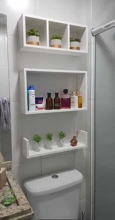 a white toilet sitting in a bathroom next to a walk in shower and shelves above it