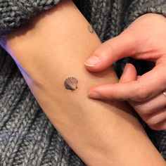 a woman with a shell tattoo on her arm