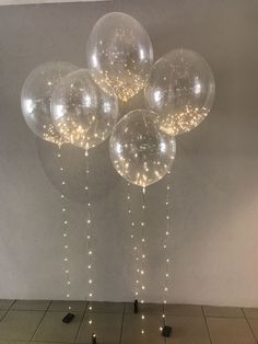 some clear balloons are hanging from the ceiling in front of a white wall and tiled floor