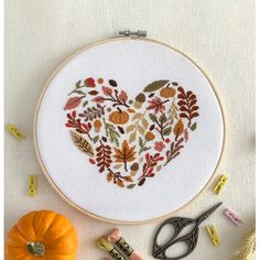 an embroidered heart surrounded by autumn leaves and scissors