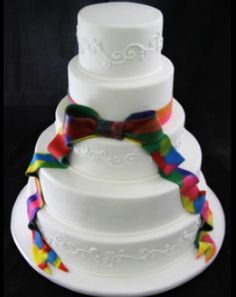 a multi - tiered wedding cake with colorful ribbons on the top and bottom layer