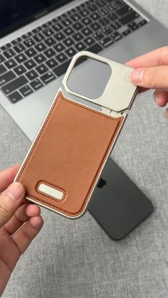 a person holding an iphone case in front of a laptop