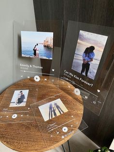 a wooden table topped with pictures and magnets next to a wall mounted photo frame