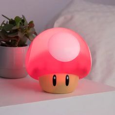 a mushroom shaped light sitting on top of a table next to a potted plant