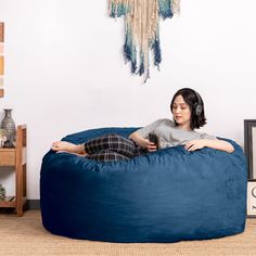 a woman is sitting on a bean bag chair with headphones in her ears and listening to music