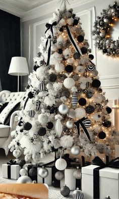 a white christmas tree decorated with black and silver baubles, ornaments and presents