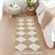 a white and brown rug on the floor next to a bed