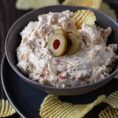 a black bowl filled with potato chips and an apple slice on top of the dip