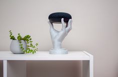 a white table topped with two vases and a hand statue on top of it