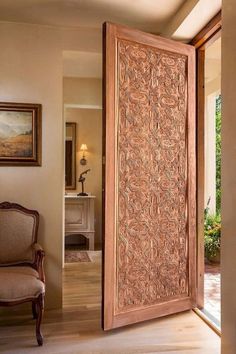 an open door in a living room next to a chair and painting on the wall