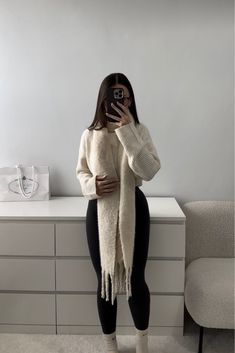 a woman taking a selfie with her cell phone in front of a white dresser