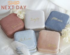 four personalized velvet jewelry cases sitting on a white sheet with flowers in the background