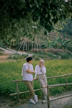 two women standing next to each other in front of a field full of yellow flowers