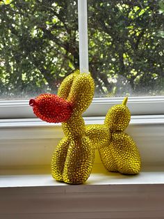 a yellow stuffed animal sitting on top of a window sill