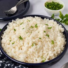 a bowl filled with rice and garnished with parsley next to other dishes