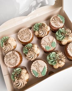 a box filled with cupcakes covered in frosting and decorated with green leaves