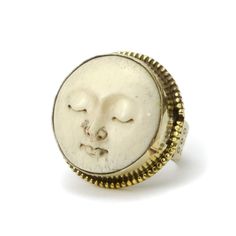 a white and gold ring with an image of a face in the middle of it