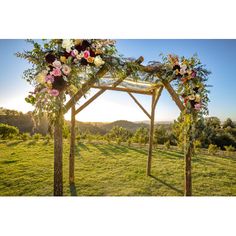 an outdoor wedding ceremony setup with flowers and greenery on the arch, overlooking mountains