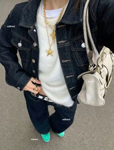 a woman in white shirt and jean jacket holding a purse with her hand on her hip