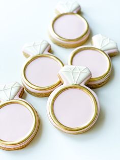 pink and gold decorated cookies are arranged on a white table top with golden trimmings