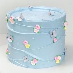 a blue cake with flowers and butterflies on it's top is featured in this post