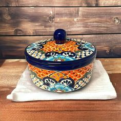 a blue and orange pot sitting on top of a wooden table next to a white towel