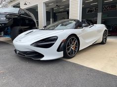 a white sports car parked in front of a garage