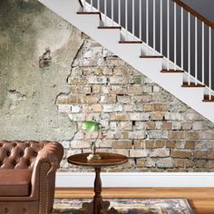 a living room with a couch and chair next to a stair case in front of a brick wall