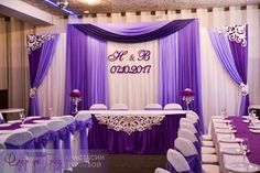 a purple and white wedding reception setup with drapes on the back wall, decorated with lace