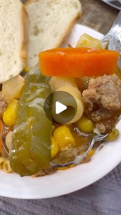 a white plate topped with meat and veggies covered in gravy next to bread