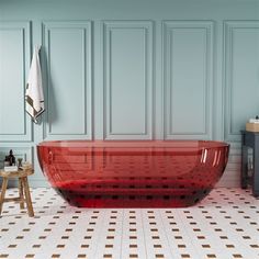 a red bath tub sitting on top of a tiled floor next to a wooden table