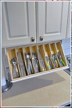 an organized kitchen drawer with utensils and spoons in the bottom compartment, on top of a countertop