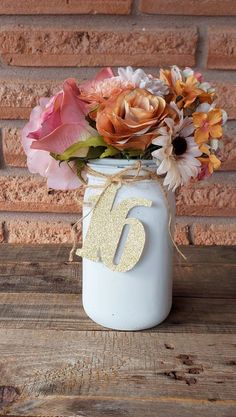 a white mason jar filled with flowers on top of a wooden table