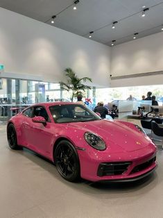 a pink sports car is parked in a showroom