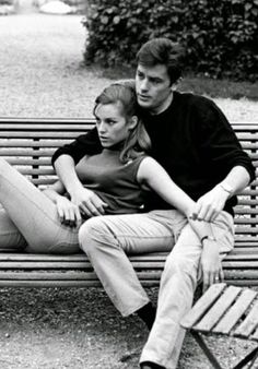 black and white photograph of two people sitting on a park bench with their arms around each other