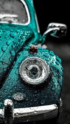 an old green car covered in water droplets and with a clock on it's hood