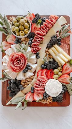 an assortment of cheeses, fruits and meats on a platter with olives