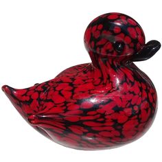 a red and black glass duck sitting on top of a white surface