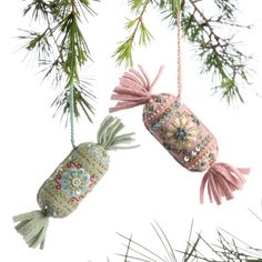 two ornaments hanging from a pine tree