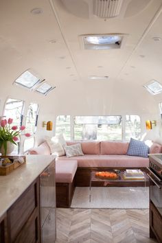 the inside of a camper with pink couches and coffee table