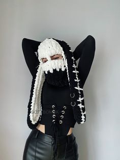 a woman wearing black pants and a white knitted mask