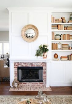 a living room with a fire place and bookshelves on the wall behind it