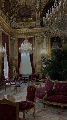 an ornately decorated living room with chandelier and red velvet couches in the center