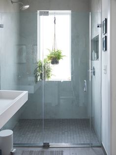 a bathroom with a shower, sink and toilet in it's corner area next to a window